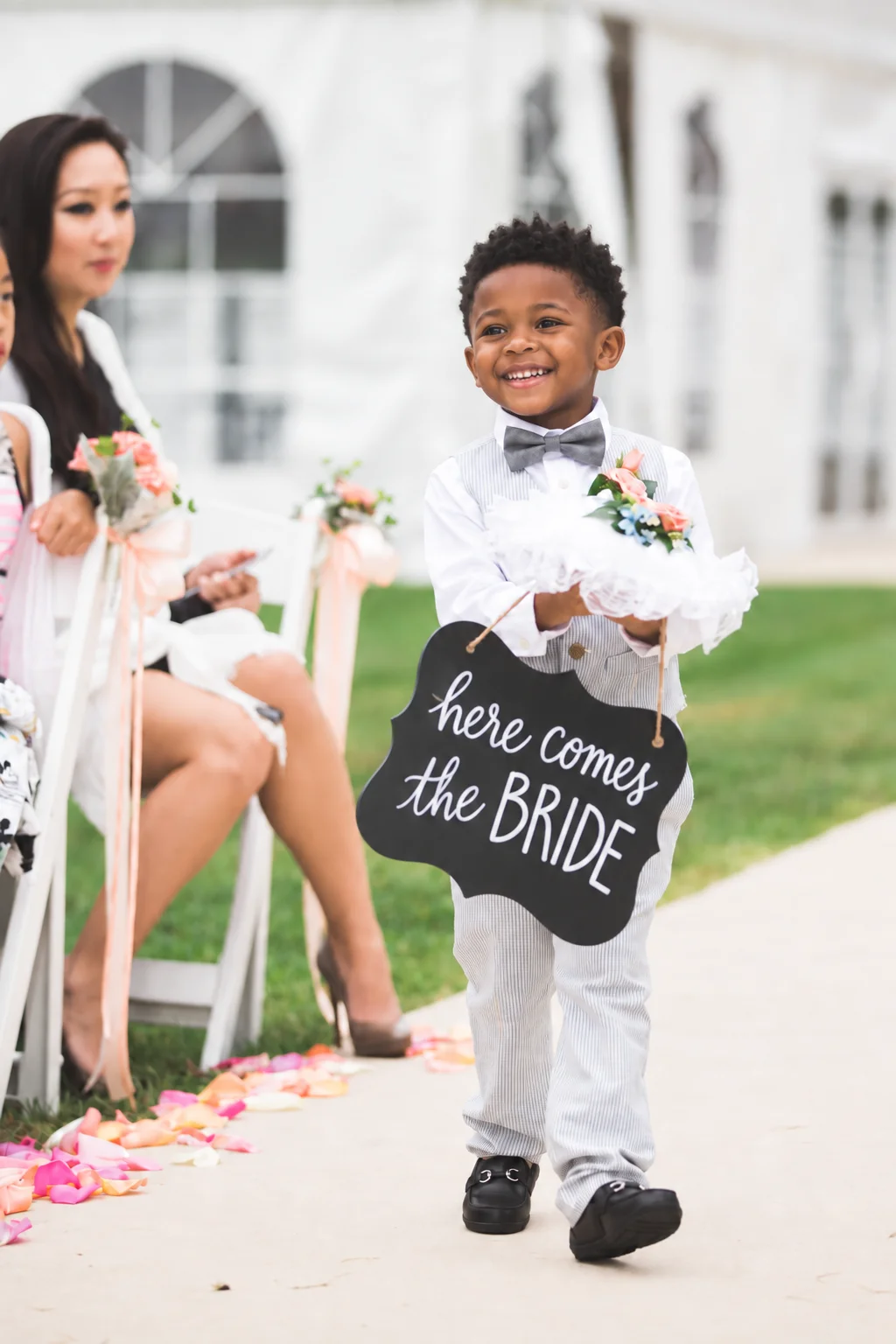 Young wedding attendant carrying a Here Comes the Bride sign